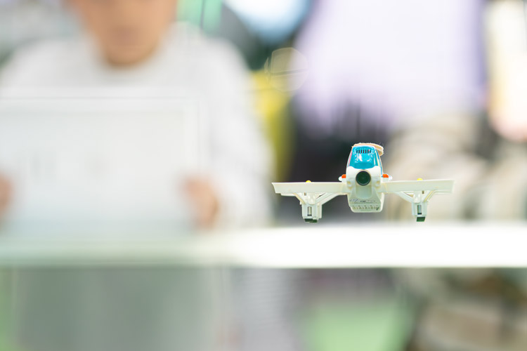 子どもたちがプログラミングした小型ドローンが空中を舞う