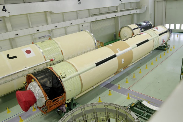 H2A最終50号機の第1段(中央)と、第2段と黒い段間部が結合したもの(右奥)。左奥に、製造中のH3の一部が写り込んだ=先月25日