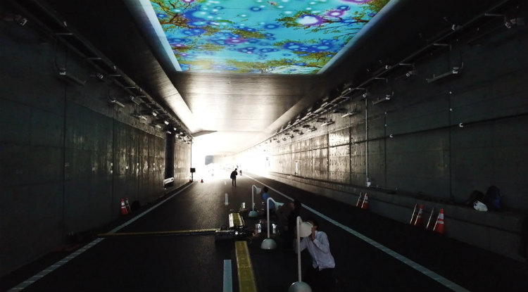 東京外かん松戸インターチェンジ開通プレイベントで披露された「未来トンネル」。トンネル内に設置されたチューブから、富士山麓の森の鳥のさえずりや風の音が聞こえ、チューブに話しかけた声は森に送られる。チューブを通した音は、トンネルの天井に映し出された映像の中に、鳥の姿や光の輪となって視覚化される。 (画像提供/清水陽子)